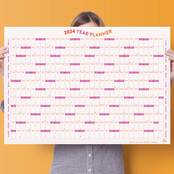 A1 size wall planner. 2024 year planner, January to December. Pink and Orange. Highlighed weekends, week numbers and moon phases. 100% Recycled Paper. Made in the UK.